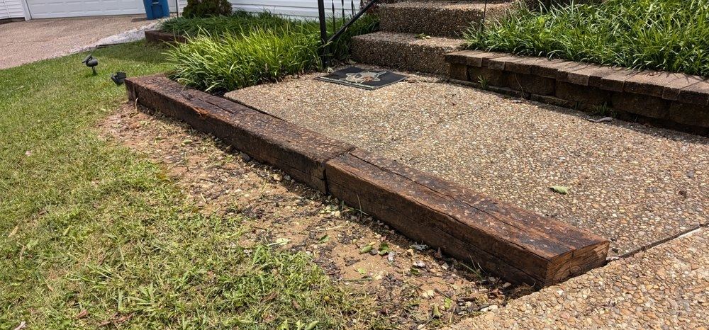 The same steps cleared, with heavy railroad ties set as a new border and the ground graded back to the concrete.